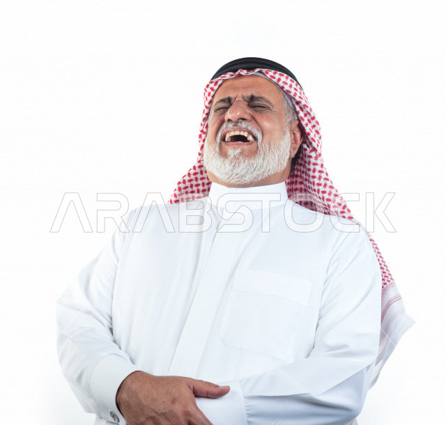 بورتريه رجل عربي سعودي كبير بالسن بإيدي متقاطعة وحالة من السعادة والفرح , يرتدي ثوب أبيض مع شماغ وعقال , خلفية بيضاء , رجل مسن يضحك ويبتسم مفهوم تعبيرالوجه 