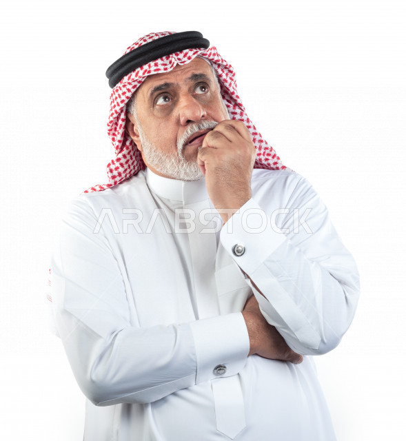 بورتريه رجل عربي سعودي كبير بالسن ينظر للأعلى يفكر ويتأمل , يرتدي ثوب أبيض مع شماغ وعقال , خلفية بيضاء , رجل مسن مهموم يفكر بتأني مفهوم تعبيرالوجه 
