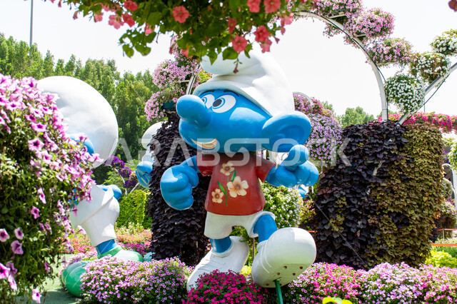 Spending fun times in public areas, a 3D model of Smurf in blue among the trees inside the Miracle Garden, famous tourist attractions, gardens in the United Arab Emirates, interest in planting flowers in the Smurf Village in Dubai, ideal entertainment destinations for children