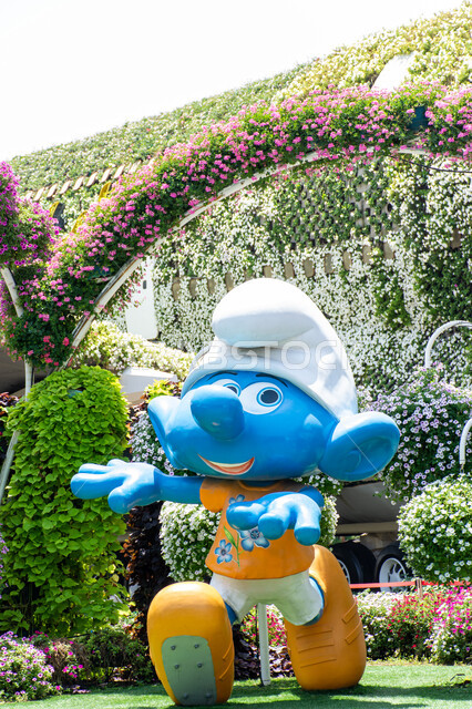 مجسم ثلاثي الابعاد لسنفور باللون الازرق بين الاشجار داخل حديقة ميركل غاردن, الاهتمام في زراعة الازهار في قرية السنافر في دبي، وجهات مثالية ترفيهية للأطفال, معالم سياحية مشهورة ,الحدائق في الإمارات العربية المتحدة ,قضاء اوقات ممتعة في المناطق العامة