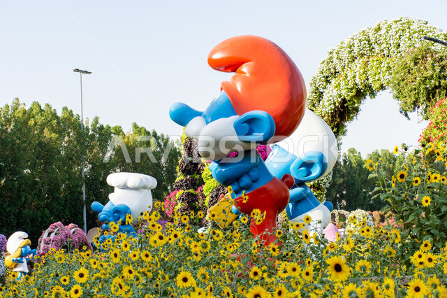 قضاء اوقات ممتعة في المناطق العامة, مجسم ثلاثي الابعاد لبابا سنفور باللون الازرق بين الاشجار داخل حديقة ميركل غاردن, الحدائق في الإمارات العربية المتحدة ,وجهات مثالية ترفيهية للأطفال, معالم سياحية مشهورة , الاهتمام في زراعة الازهار في قرية السنافر في دبي