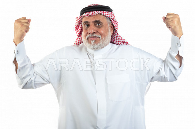بورتريه رجل عربي سعودي كبير بالسن يقوم بحركة العضلات ذات الرأسين , يرتدي ثوب أبيض مع شماغ وعقال , خلفية بيضاء , رجل مسن ذو صحة بحركة العضلات ذات الرأسين وممارسة اللياقة البدنية مفهوم تعابيرالوجه ولغة الجسد المختلفة