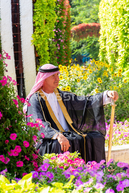 Distinctive agricultural engineering in the United Arab Emirates, a foreign tourist wearing traditional dress in Miracle Garden, having fun in public parks, taking care of planting trees and flowers in parks, famous recreational tourist attractions