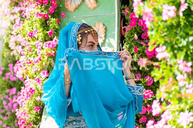 Spending fun times in public parks, distinguished agricultural engineering in the United Arab Emirates, famous recreational tourist attractions, interest in planting trees and flowers in parks, close-up of a foreign tourist wearing traditional Arab dress in Miracle Garden