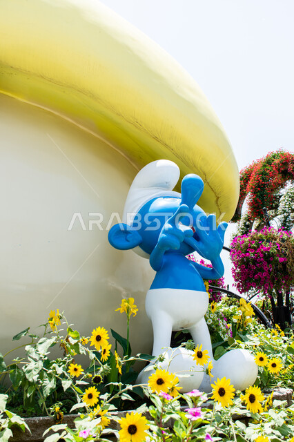 Ideal entertainment destinations for children, a close-up of a 3D model of a blue Smurf inside the Miracle Garden, interest in planting flowers in the Smurfs Village in Dubai, famous tourist attractions, enjoying the natural scenery in the gardens of the United Arab Emirates