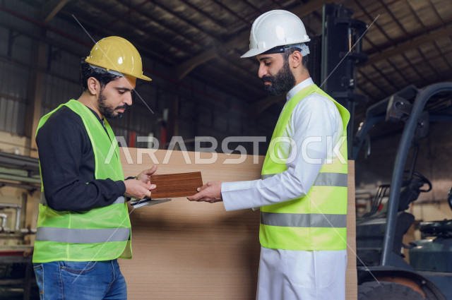 مهندسان  سعوديان عاملان يشرفان في داخل المصنع في المملكة العربية السعودية , إرتداء خوذة وسترة الحماية الخاصة بالعمل , العامل المسؤول بخوذة صفراء , المهندس المشرف بخوذة بيضاء , فحص المعدات بأنفسهم , تدقيق العمل , الإشراف والنقاش في العمل
