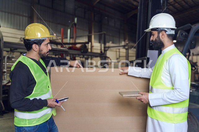 مهندسان  سعوديان عاملان يشرفان في داخل المصنع في المملكة العربية السعودية , إرتداء خوذة وسترة الحماية الخاصة بالعمل , العامل المسؤول بخوذة صفراء , المهندس المشرف بخوذة بيضاء , فحص المعدات بأنفسهم , تدقيق العمل , الإشراف والنقاش في العمل