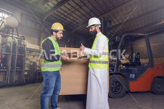 مهندسان  سعوديان عاملان يشرفان في داخل المصنع في المملكة العربية السعودية , إرتداء خوذة وسترة الحماية الخاصة بالعمل , العامل المسؤول بخوذة صفراء , المهندس المشرف بخوذة بيضاء , فحص المعدات بأنفسهم , تدقيق العمل , الإشراف والنقاش في العمل