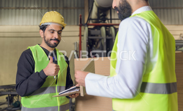 مهندسان  سعوديان عاملان يشرفان في داخل المصنع في المملكة العربية السعودية , إرتداء خوذة وسترة الحماية الخاصة بالعمل , العامل المسؤول بخوذة صفراء , المهندس المشرف بخوذة بيضاء , فحص المعدات بأنفسهم , تدقيق العمل , الإشراف والنقاش في العمل