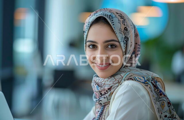 Administrative office jobs and professions, business affairs management and organization, a veiled Saudi Arabian Gulf female employee sitting in an office looking at the camera with gestures of joy and happiness, companies and offices in the Kingdom of Saudi Arabia