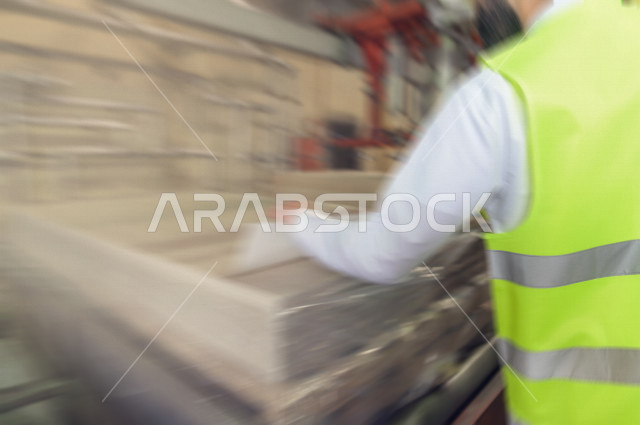 صورة مقربة ليد المهندس السعودي يقوم بالإشراف في داخل المصنع في المملكة العربية السعودية , إرتداء سترة الحماية الخاصة بالعمل , فحص المعدات, تدقيق العمل , الفحص والإشراف