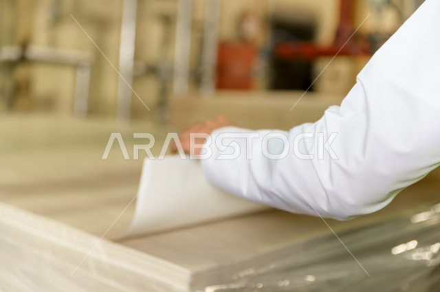 Close-up of the hand of the Saudi engineer supervising inside the factory in the Kingdom of Saudi Arabia, wearing the work protection jacket, checking the equipment, checking the work, checking and supervising