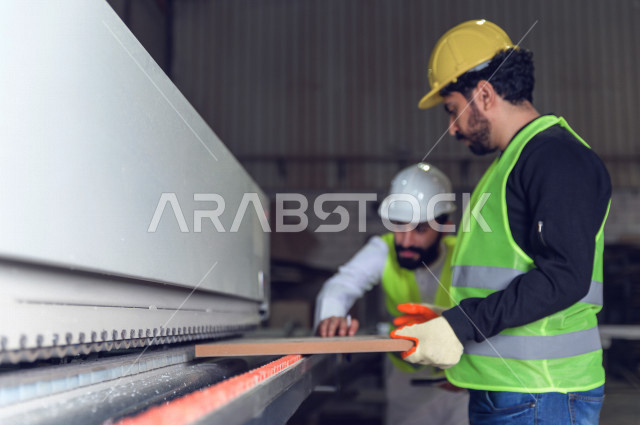 مهندسان  سعوديان عاملان يشرفان في داخل المصنع في المملكة العربية السعودية , إرتداء خوذة وسترة الحماية الخاصة بالعمل , العامل المسؤول بخوذة صفراء , المهندس المشرف بخوذة بيضاء , فحص المعدات بأنفسهم , تدقيق العمل , الإشراف والنقاش في العمل