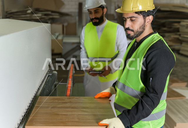 مهندسان  سعوديان عاملان يشرفان في داخل المصنع في المملكة العربية السعودية , إرتداء خوذة وسترة الحماية الخاصة بالعمل , العامل المسؤول بخوذة صفراء , المهندس المشرف بخوذة بيضاء , فحص المعدات بأنفسهم , تدقيق العمل , الإشراف والنقاش في العمل