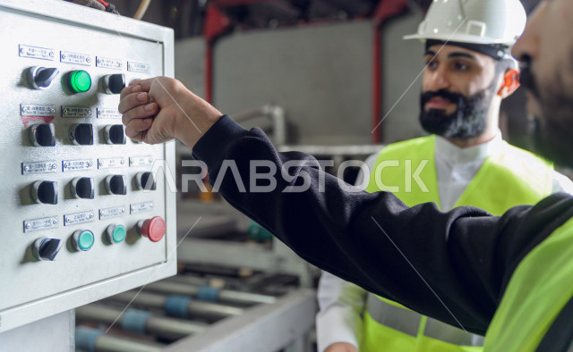 مهندس ومشرف سعودي يرتدي خوذه بيضاء يشرف داخل المصنع في المملكة العربية السعودية , ارتداء خوذة وسترة الحماية الخاصة بالعمل , التصنيع والإشراف والتدقيق في العمل , الهندسة والصناعة