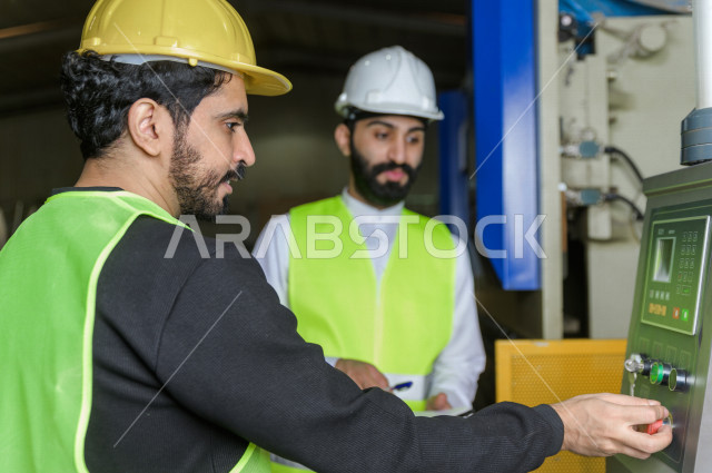 مهندسان  سعوديان عاملان يشرفان في داخل المصنع في المملكة العربية السعودية , إرتداء خوذة وسترة الحماية الخاصة بالعمل , العامل المسؤول بخوذة صفراء , المهندس المشرف بخوذة بيضاء , فحص المعدات بأنفسهم , تدقيق العمل , الإشراف والنقاش في العمل
