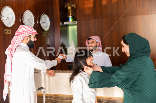 عائلة سعودية تقوم بإجراءات الحجز والدخول لدى مكتب الاستقبال في الفندق , سياحة وفندقة , رحلة عائلية سعيدة