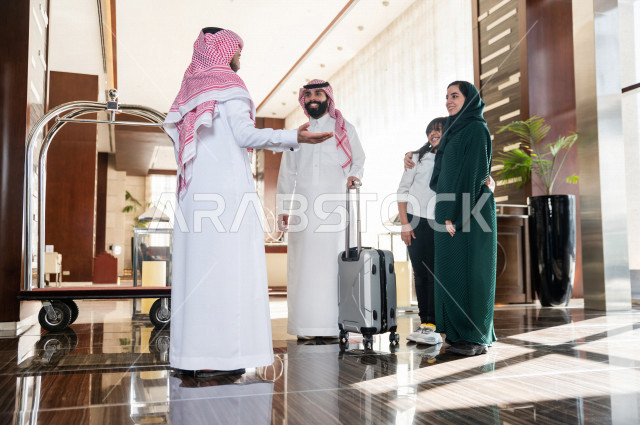 A Saudi male and female tourist hand over bags to a baggage operator at the entrance to a hotel