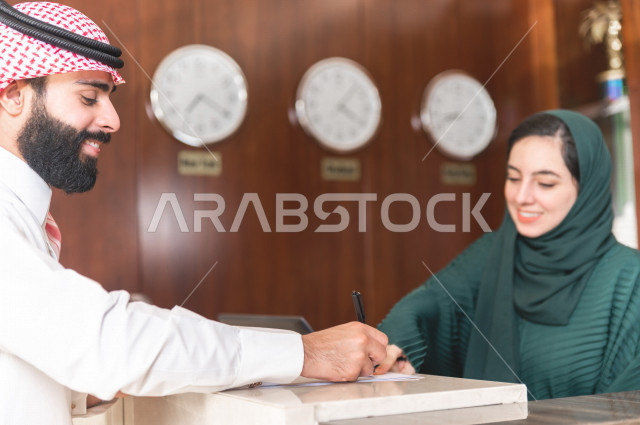 رجل وامرأة سعوديان يجلسان على طاولة مطعم يتحدثان وينتظران الطلب 