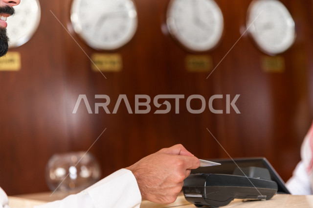 صورة مقربة لسائح خليجي سعودي يقوم بإجراءات الحجز والدخول لدى مكتب الاستقبال في الفندق , سياحة وفندقة 