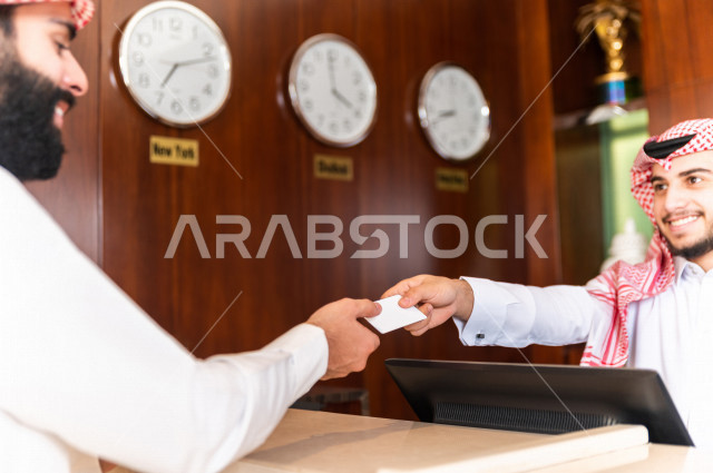 سائح خليجي سعودي يقوم بإجراءات الحجز والدخول لدى مكتب الاستقبال في الفندق , سياحة وفندقة , إستلام بطاقة الغرفة , تأكيد الحجز