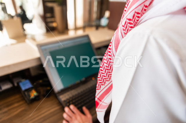 صورة مقربة لسائح خليجي سعودي يقوم بإجراءات الحجز والدخول لدى مكتب الاستقبال في الفندق , سياحة وفندقة 