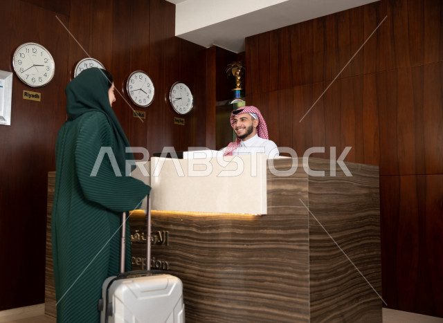 A veiled Saudi Gulf businesswoman dragging a travel bag near the reception desk at the hotel, tourism and hospitality, spending fun times
