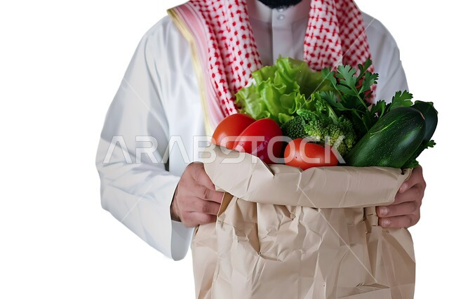 شراء الاحتياجات المنزلية، بورتريه مقرب لرجل خليجي عربي سعودي يرتدي الزي التقليدي يحمل بيده كيس الخضروات، السلع والمواد الغذائية المختلفة، الخضار الطازجة الشهية، مراكز التسوق في المملكة العربية السعودية، خلفية بيضاء