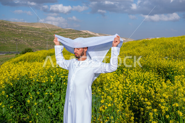 الاهتمام بالاناقة والمظهر الخارجي، الطريقة الصحيحة لارتداء العمامه الاماراتيه، التنزه في مزارع الإمارات العربية المتحدة، الاستمتاع بالمناظر الطبيعية في فصل الربيع، صورة مقربة لشاب عربي خليجي إماراتي يرتدي الكندورة يقوم بوضع العمامة، خلفية الطبيعة