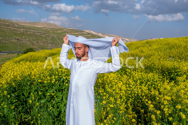 الاهتمام بالاناقة والمظهر الخارجي، الطريقة الصحيحة لارتداء العمامه الاماراتيه، التنزه في مزارع الإمارات العربية المتحدة، الاستمتاع بالمناظر الطبيعية في فصل الربيع، صورة مقربة لشاب عربي خليجي إماراتي يرتدي الكندورة يقوم بوضع العمامة، خلفية الطبيعة