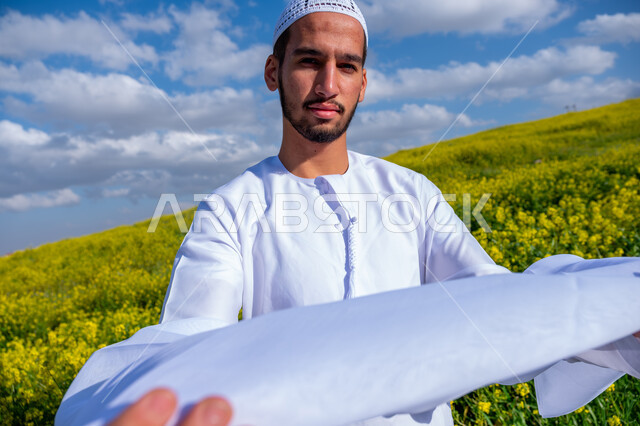 الاهتمام بالاناقة والمظهر الخارجي، الطريقة الصحيحة لارتداء العمامه الاماراتيه، التنزه في مزارع الإمارات العربية المتحدة، الاستمتاع بالمناظر الطبيعية في فصل الربيع، صورة مقربة لشاب عربي خليجي إماراتي يرتدي الكندورة يقوم بوضع العمامة، خلفية الطبيعة