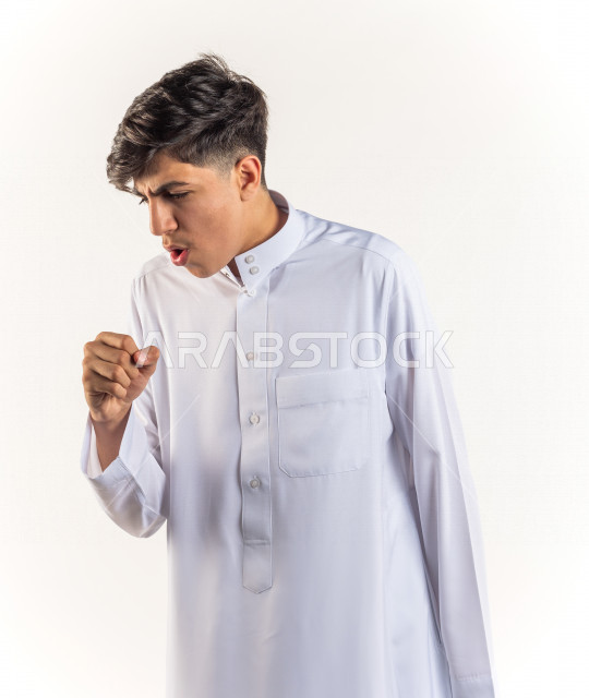 بورتريه شاب مراهق خليجي سعودي يضع يده أمام فمه وهو يسعل بإيماءات وجه ويدين مختلفة , خلفية بيضاء 