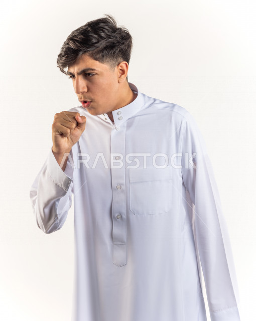 بورتريه شاب مراهق خليجي سعودي يضع يده أمام فمه وهو يسعل بإيماءات وجه ويدين مختلفة , خلفية بيضاء 