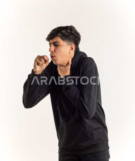 بورتريه شاب مراهق خليجي سعودي يضع يده أمام فمه وهو يسعل بإيماءات وجه ويدين مختلفة , خلفية بيضاء 