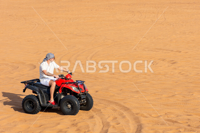 Fun youth activities in the desert environment in the United Arab Emirates, riding quad bikes in the Dubai desert, soft golden sand, safari adventures on the sand dunes, nature background.