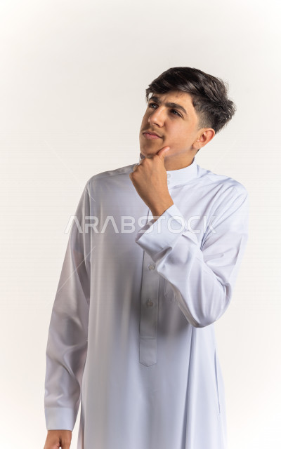 بورتريه شاب مراهق خليجي سعودي ينظر للأعلى يفكر ويتأمل بإيماءات وجه ويدين مختلفة , يرتدي ثوب أبيض , خلفية بيضاء 