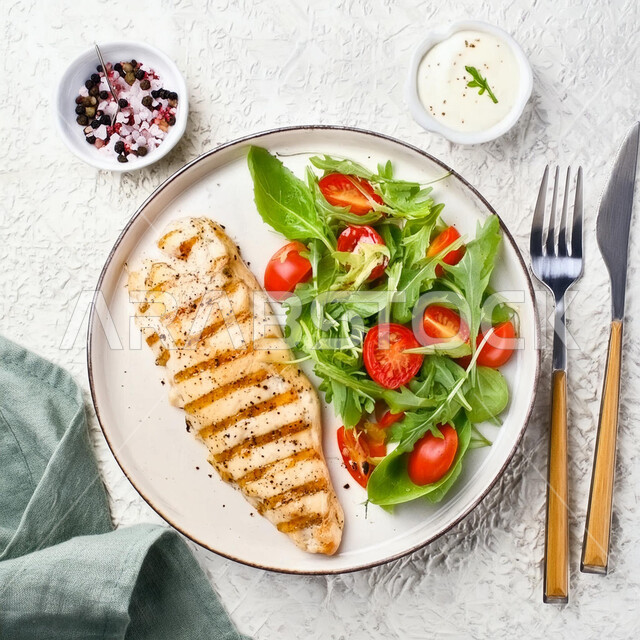 Distinctive dishes and recipes in the kitchens of the Kingdom of Saudi Arabia, delicious oriental Arabic food, fast food restaurants, healthy chicken meals, a picture from the top of a plate of fillet pieces with vegetables, a white background.