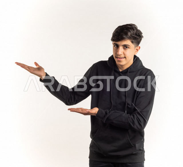 Portrait of a young Saudi Arabian Gulf teenager pointing up with different facial and hand gestures, white background