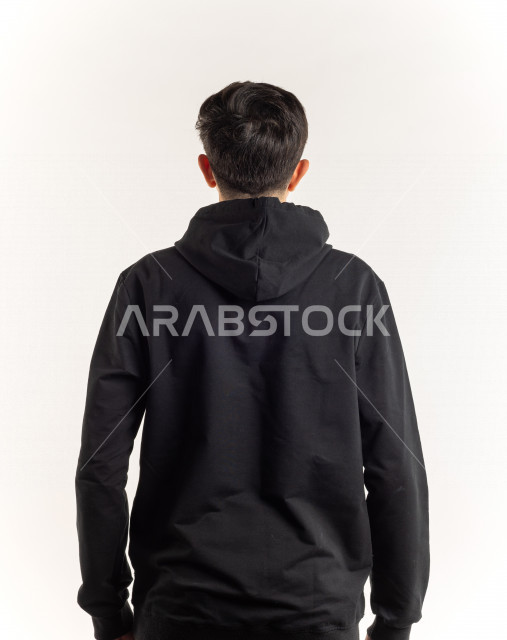 بورتريه شاب مراهق خليجي سعودي يقوم بجلسات تصوير , تصوير من الخلف لصبي يرتدي لباس أسود , خلفية بيضاء 