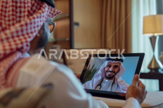 الاستفادة من التكنولوجيا والتقنيات الحديثة, رجل عربي خليجي سعودي يجلس في بيته يتلقى استشارة طبية من الطبيب عن طريق الجهاز اللوحي, تقديم الخدمات الطبية والرعاية الصحية عن بعد، مفهوم الطب والعناية بالمرضى
