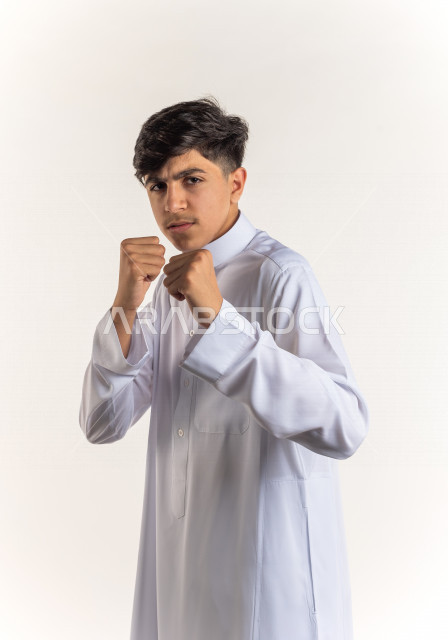 Portrait of a Saudi Gulf boy doing biceps movements with different facial and hands gestures, white background, enjoying good physical health