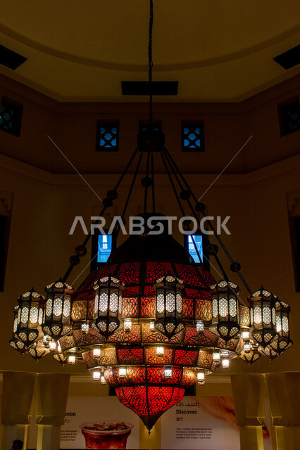 ثرية حديدية معلقة ذات فوانيس مضاءة بألوان جذابة, تصاميم وديكورات داخلية مستوحاة من التراث, إضاءة وقناديل مزخرفة داخل مبنى أثري قديم