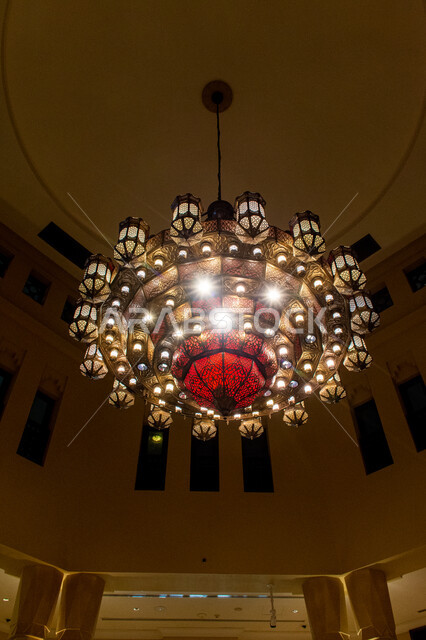 تصاميم وديكورات داخلية مستوحاة من التراث, ثرية حديدية معلقة ذات فوانيس مضاءة بألوان جذابة, إضاءة وقناديل مزخرفة داخل مبنى أثري قديم