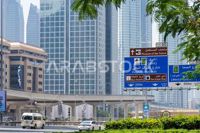 Urban renaissance in construction and streets in the Emirates, a large blue directional signboard in Arabic and English on Sheikh Zayed Road in Dubai, roads and public transportation, use of directional signs on main roads