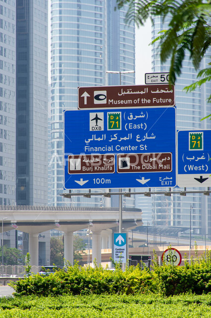 A large blue directional signboard in Arabic and English on Sheikh Zayed Road in Dubai, roads and public transportation in the Emirates, use of directional signs on main roads, urban renaissance in construction and streets.