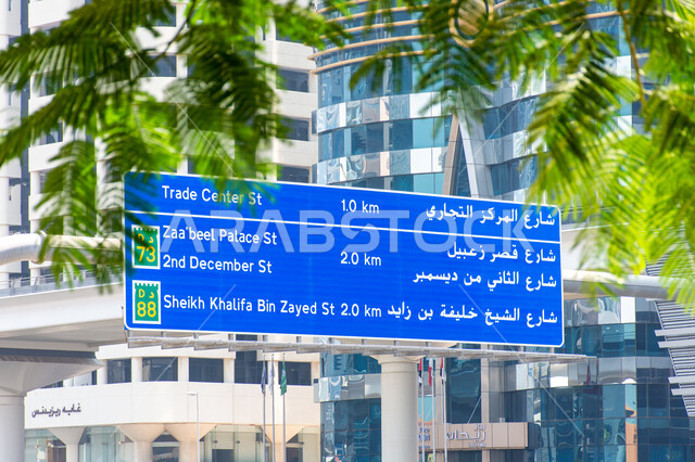 لافتة توجيهية كبيرة باللون الأزرق باللغتين العربية والإنجليزية في شارع الشيخ زايد بمدينة دبي، الطرق والمواصلات العامة في الامارات, استخدام اللوحات الإرشادية في الطرقات الرئيسية, النهضة العمرانية في البناء والشوارع
