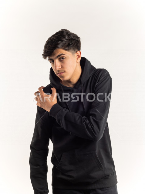 Portrait of a young Saudi Arabian Gulf teenager putting his hand on his shoulder feeling a state of aches and pain with different facial and hands gestures, white background