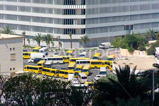 Interest in education and the cultural educational field, a high-angle shot of school buses in a school complex in Dubai, United Arab Emirates, means of transporting male and female students to and from school, safe transportation for children’s transportation
