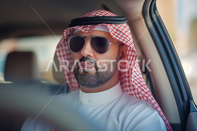 Transportation in Saudi Arabia, concept of elegance and touring, interest in appearance, gestures of seriousness and self-confidence, close-up of a Saudi Arabian Gulf man wearing traditional dress and sunglasses sitting inside his car