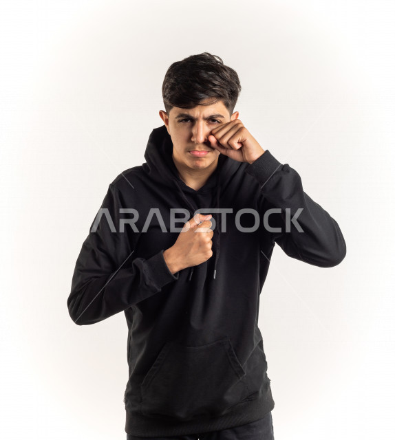 Portrait of a young Saudi Arabian Gulf teenager with different facial and hand gestures indicating crying and sadness, white background